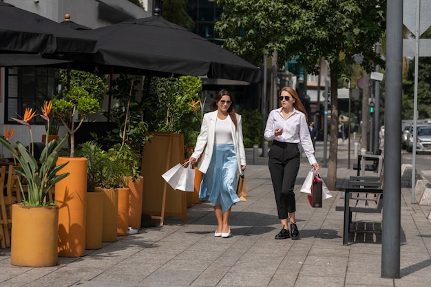 Amigos caminando por la calle felices cargando bolsas después de ir de compras en una zona comercial