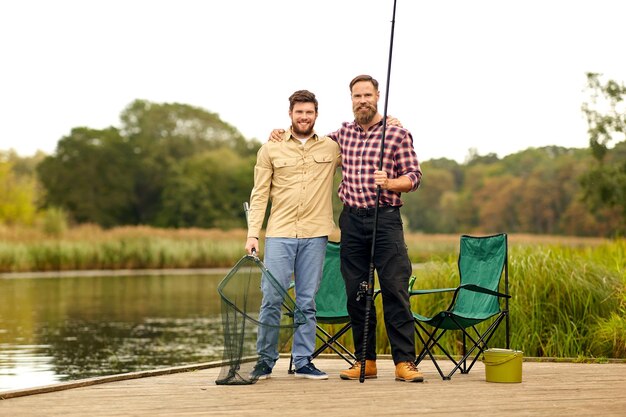 amigos con caña y red de pesca en un lago o río