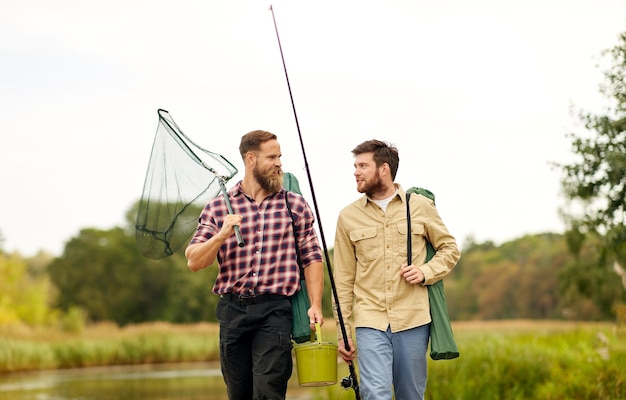 amigos con cañas de pescar y red en un lago o río