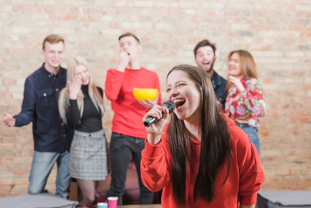 Foto amigos cantando al karaoke en una fiesta