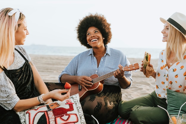 Amigos cantando juntos en un picnic en la playa