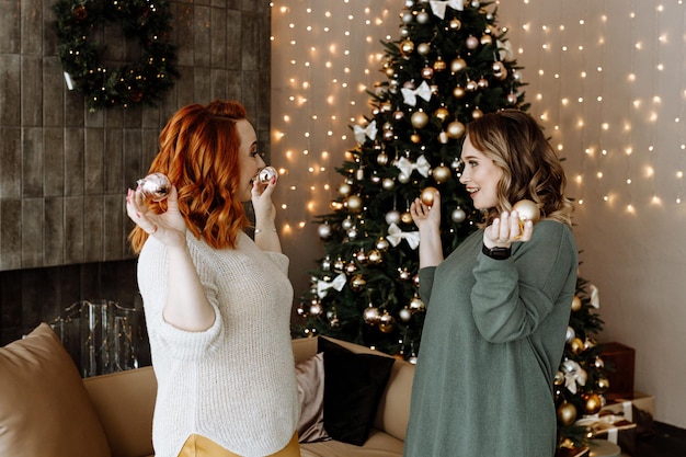 amigos celebram o Natal em casa no fundo de uma linda árvore de Natal