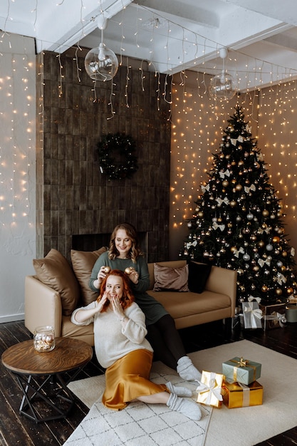 amigos celebram o Natal em casa no fundo de uma linda árvore de Natal