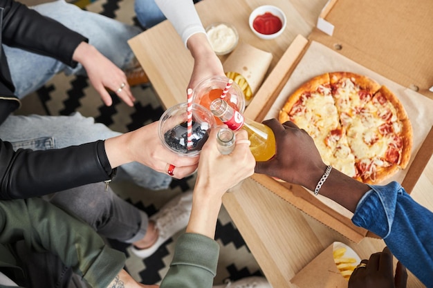 Amigos celebrando con limonadas y pizza