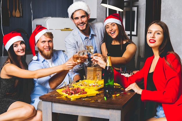 Amigos celebrando la víspera de Navidad o año nuevo. Mesa de fiesta con champagne