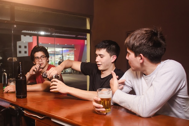 Amigos charlando mientras beben una cerveza en el bar.