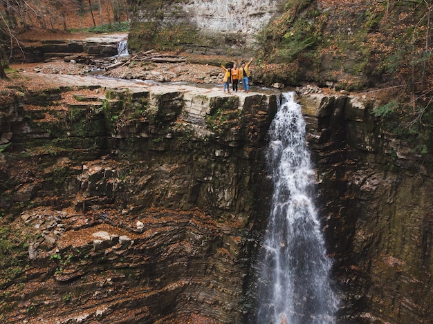 Amigos en la cima de la temporada de otoño de la cascada