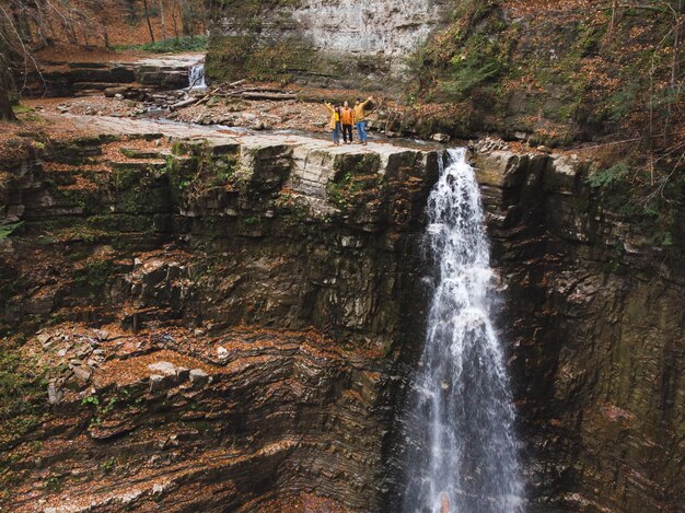 Amigos en la cima de la temporada de otoño de la cascada