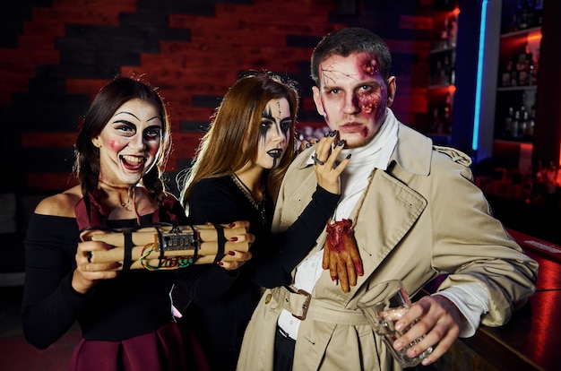 Amigos com a bomba nas mãos estão na festa de halloween temática com maquiagem e fantasias assustadoras.