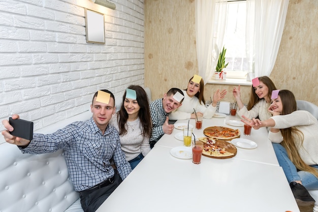 Amigos com adesivos brincando de 'Adivinha quem' e fazendo selfie