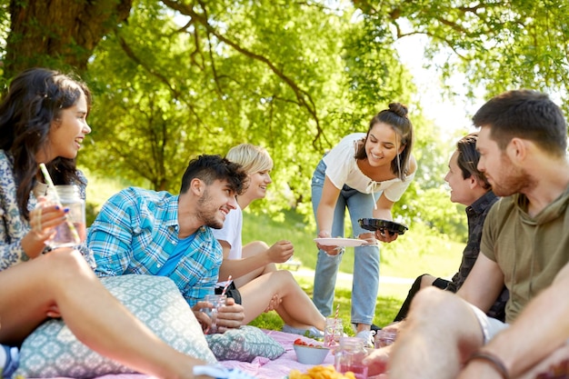 amigos com bebidas e comida em um piquenique no parque