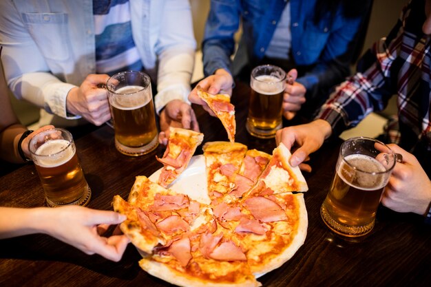 Amigos com caneca de cerveja e pizza no bar