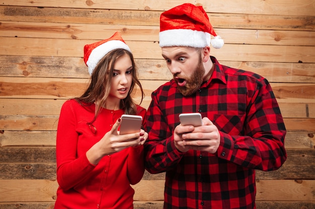 Amigos com chapéu de Papai Noel com telefones