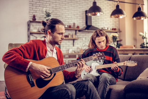 Amigos com guitarras. Dois melhores amigos sentindo-se realmente felizes tocando violão no fim de semana