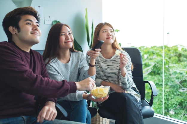 Amigos comendo batatas fritas enquanto assistem tv juntos