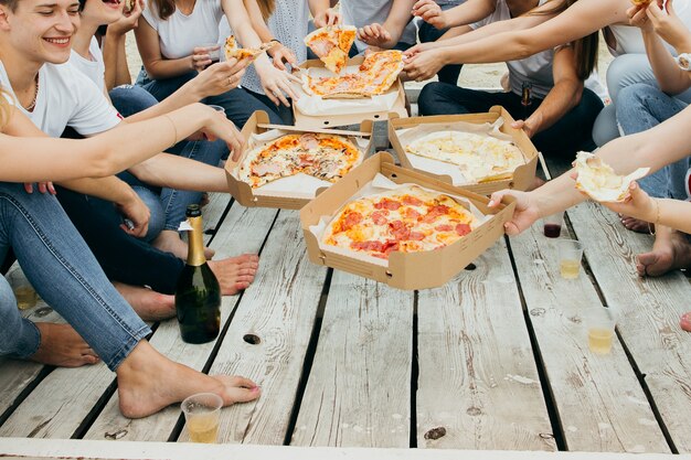 Foto amigos comendo pizza no cais de madeira