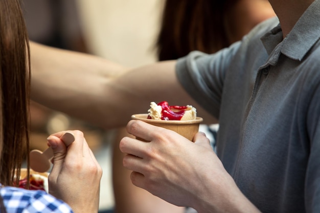 Amigos comiendo helado al aire libre manos sosteniendo tazas closeup copia espacio