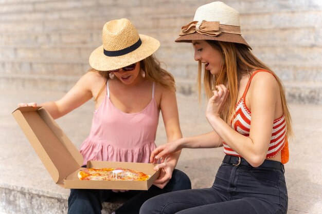 Amigos comiendo pizza en la ciudad disfrutando de las vacaciones uno de los amigos muy feliz de abrir la caja de pizza