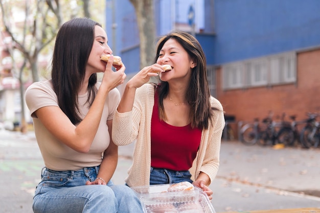 Amigos compartilhando pães doces sentados em um parque da cidade