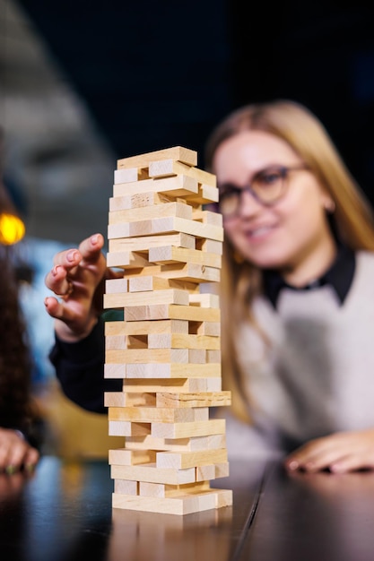 Amigos construyen una torre con bloques de madera en la mesa concepto de trabajo en equipo Juego de mesa jenga enfoque selectivo