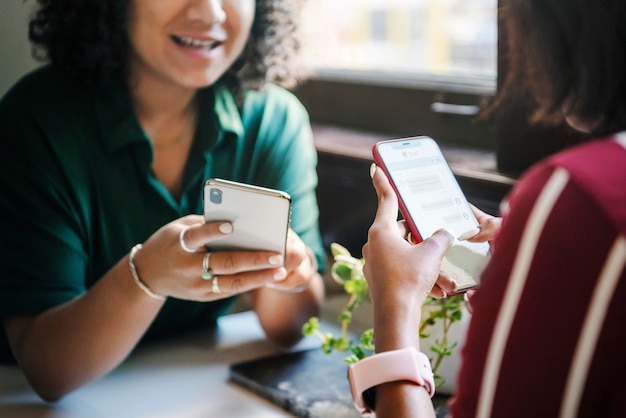 Amigos conversando enquanto mandam mensagens de texto em um café