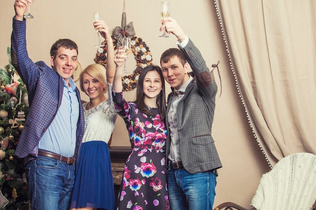 Amigos de cuatro hombres y mujeres con bacale celebran con champán en el interior de Navidad
