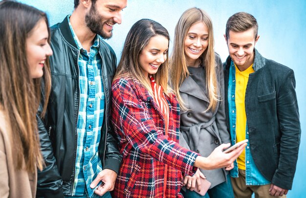 Amigos da geração do milênio em um momento viciado usando smartphones móveis