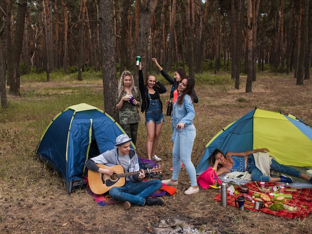 Amigos dançando com um violão. o turista descansa na natureza. estilo de vida de acampamento