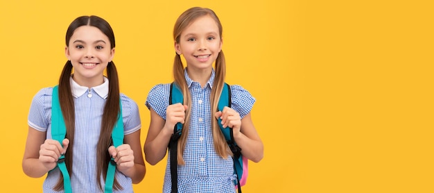 Amigos das meninas da escola Crianças felizes de volta à escola no dia do conhecimento, 1º de setembro, fundo amarelo