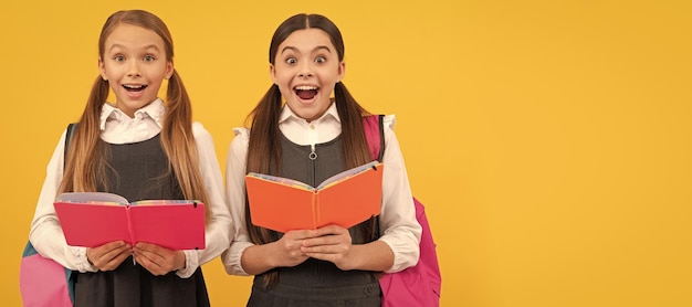 Amigos das meninas da escola Crianças surpresas em uniformes formais leem livros escolares fundo amarelo