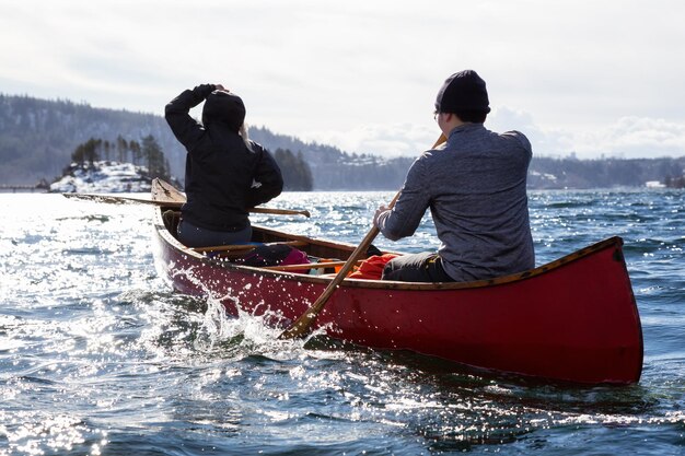 Amigos de casal em uma canoa de madeira pelas montanhas canadenses