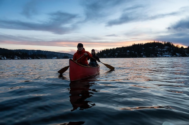 Amigos de casal em uma canoa de madeira pelas montanhas canadenses