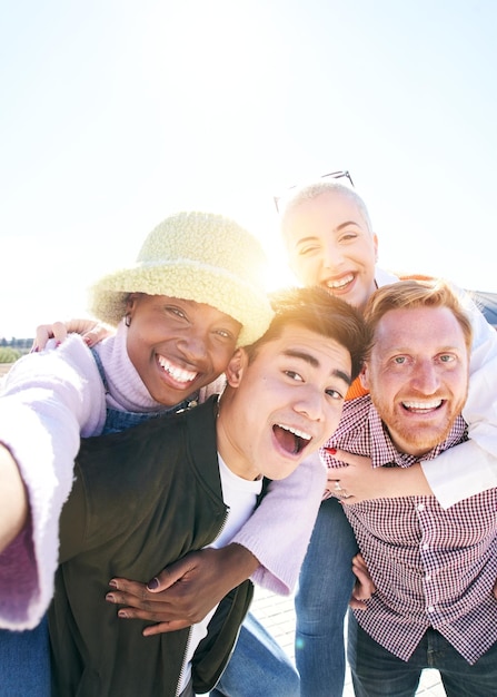 Foto amigos de costas verticais tirando uma selfie sorridente juntos ao ar livre em um retrato de um dia ensolarado