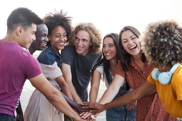 Amigos de diferentes etnias se empilhando e olhando uns para os outros grupos de pessoas se divertindo