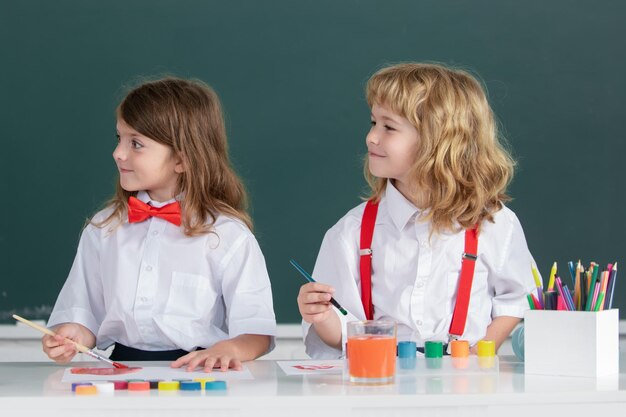 Amigos de escola bonitos crianças desenhando e pintando na escola, garoto amigável, uma garota, alunos engraçados desenham amigos