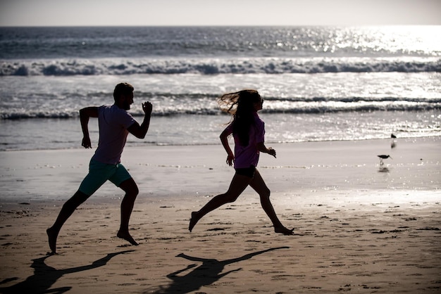 Amigos de esporte e estilo de vida saudável correndo ao pôr do sol na praia silhueta casal correndo na praia