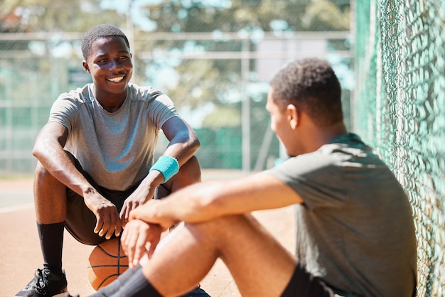 Amigos de esportes e atletas de basquete conversam após exercícios de treinamento e conversas de jogos ao ar livre na quadra de basquete, falando sobre a estratégia da equipe em uma pausa relaxante do condicionamento físico