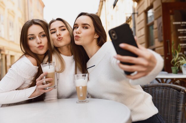 Amigos de garota tomando uma selfie em uma mesa de café