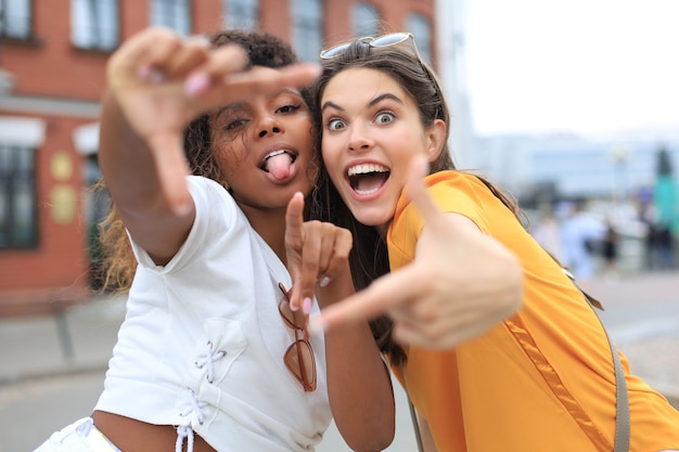 Amigos de lindas garotas se divertindo juntos, tirando uma selfie na cidade.