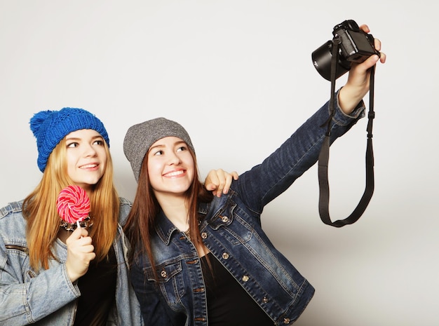 Amigos de meninas felizes tirando algumas fotos sobre fundo cinza