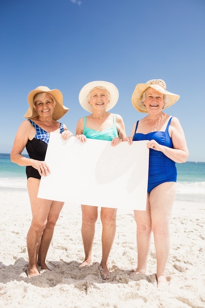 Amigos de mulher sênior segurando papel em branco