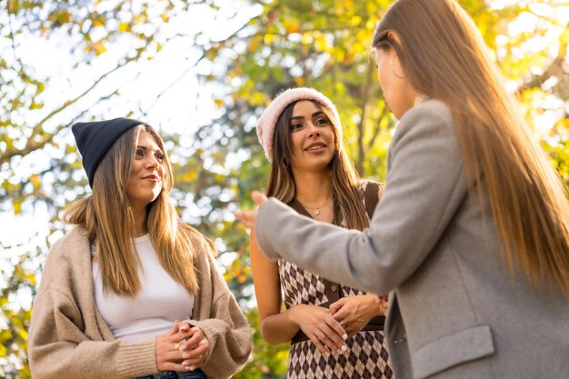 Amigos de mulheres de estilo de vida de outono sorrindo em um parque no outono ao pôr do sol