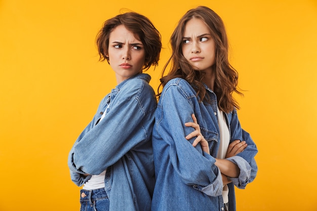 Foto amigos de mulheres jovens descontentes agressivos isolados sobre uma briga de parede amarela.