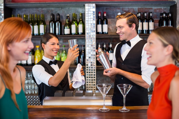 Amigos de pé no balcão enquanto barman preparando uma bebida