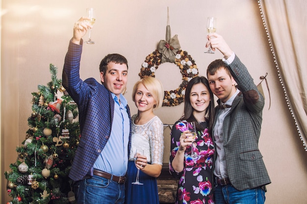 Amigos de quatro homens e mulheres com bacale celebram com champanhe no interior do Natal