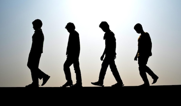 Foto amigos de silhueta em fila andando no campo