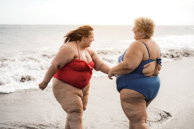 Amigos de tamanho grande caminhando na praia se divertindo durante as férias de verão