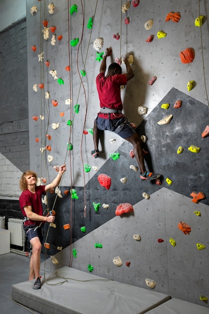 Amigos de tiro completo escalando a parede juntos