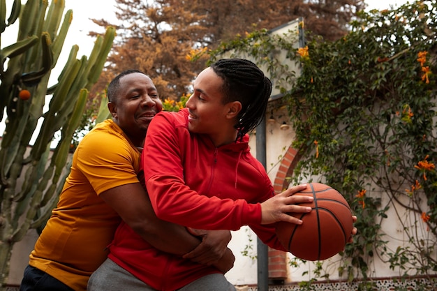 Amigos de tiro médio jogando basquete ao ar livre