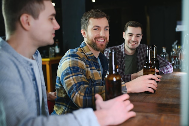 Amigos descansando no pub com cerveja nas mãos conversando